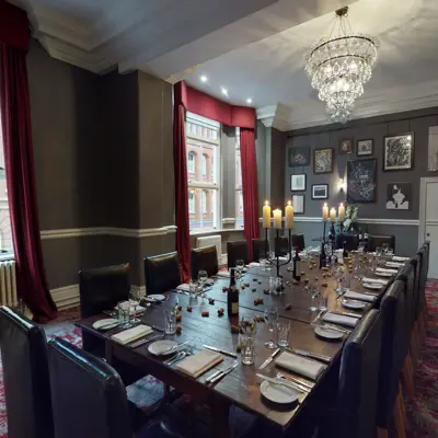 A dining room featuring a lengthy table adorned with an elegant chandelier.