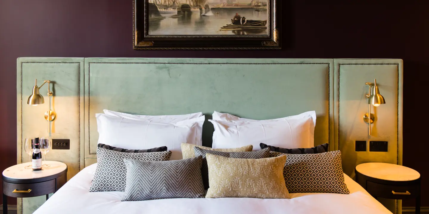 An elegantly made bed adorned with plush pillows and complemented by a captivating wall painting.