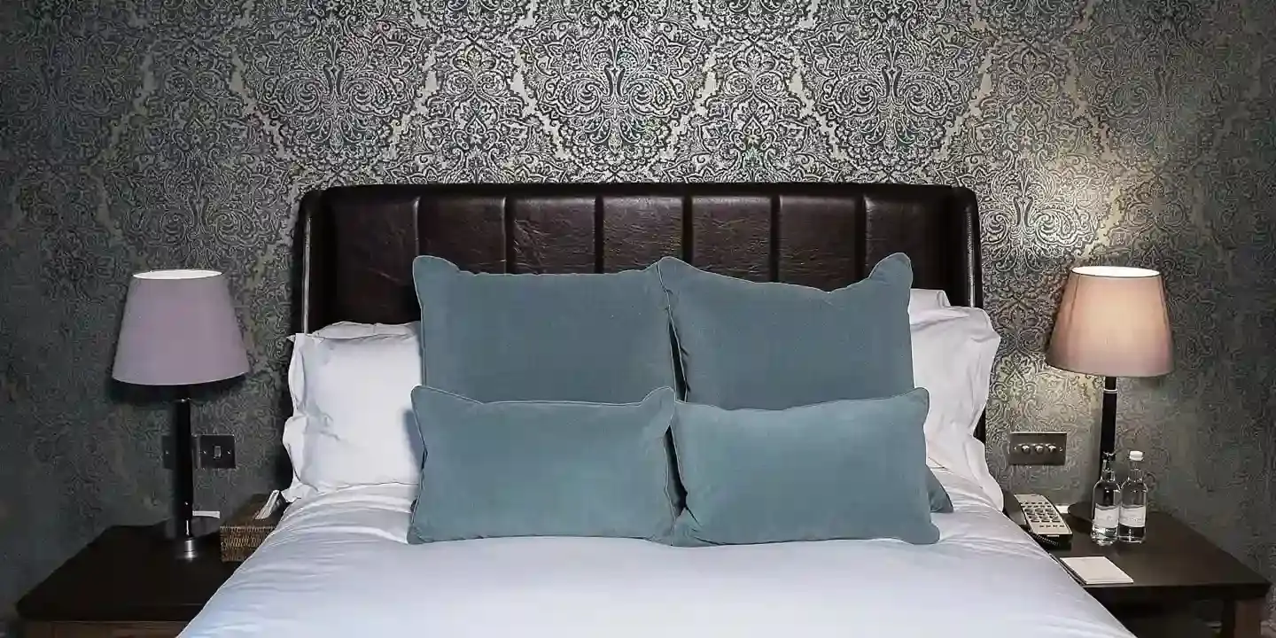Bed with two blue pillows atop it.