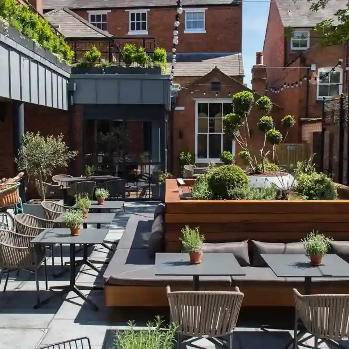 A patio with tables, chairs, and plants.