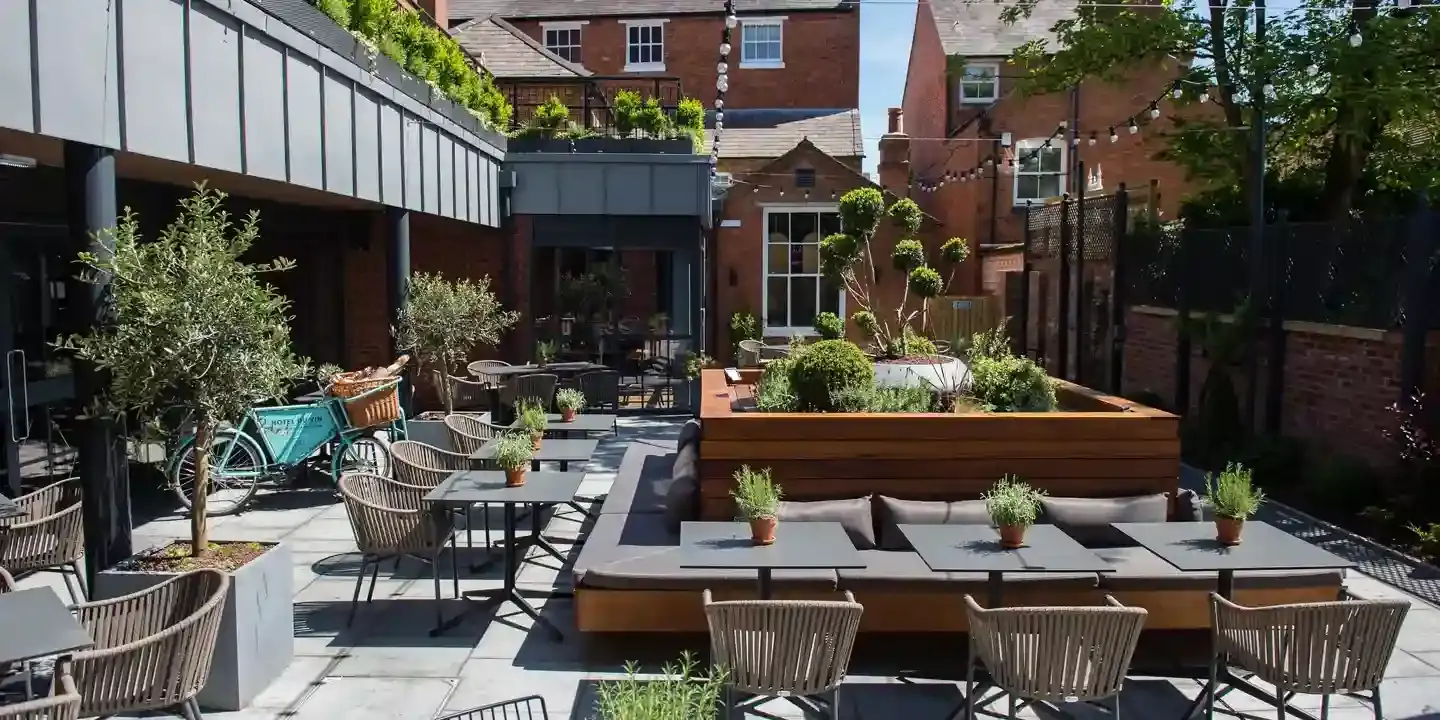 A patio with tables, chairs, and plants.