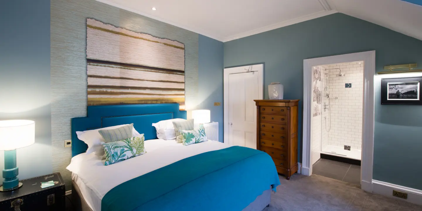 Bedroom featuring a comfortable bed, elegant dresser, and captivating wall painting.