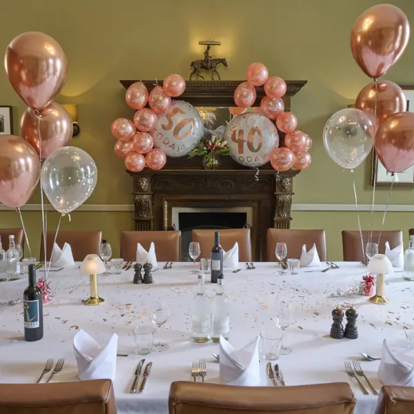 A long table decorated with confetti. There are pink and white balloons across the table