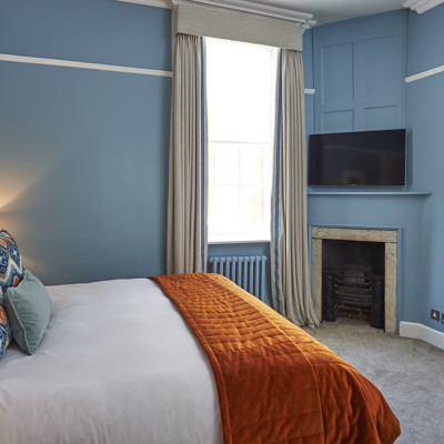 Neatly arranged bedroom featuring a well-made bed and a flat-screen TV.