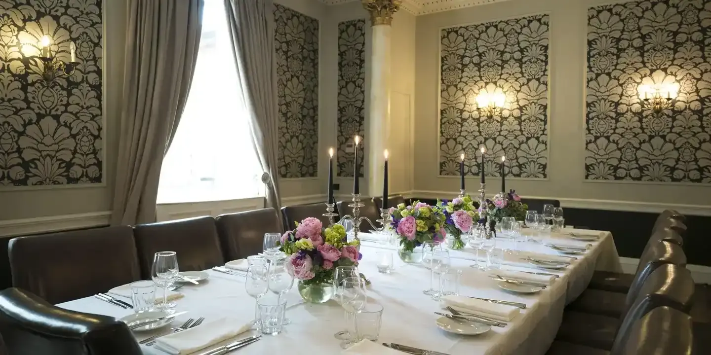 Table elegantly set for a formal dinner, adorned with candles and flowers.