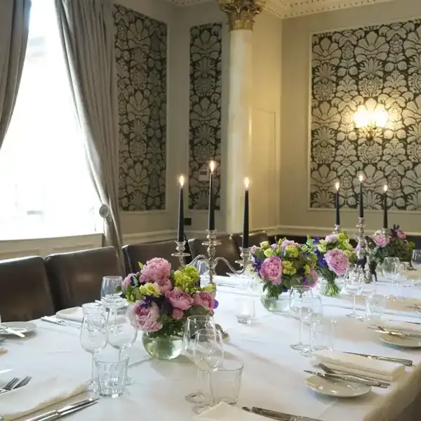 Table elegantly set for a formal dinner, adorned with candles and flowers.