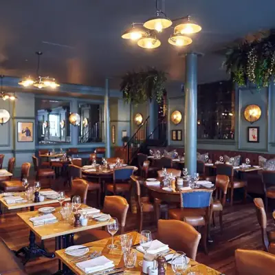 A restaurant featuring numerous tables and chairs with plants hanging from ceiling