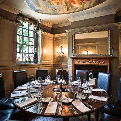 Table set for a formal dinner with place settings. There is a painting on the roof