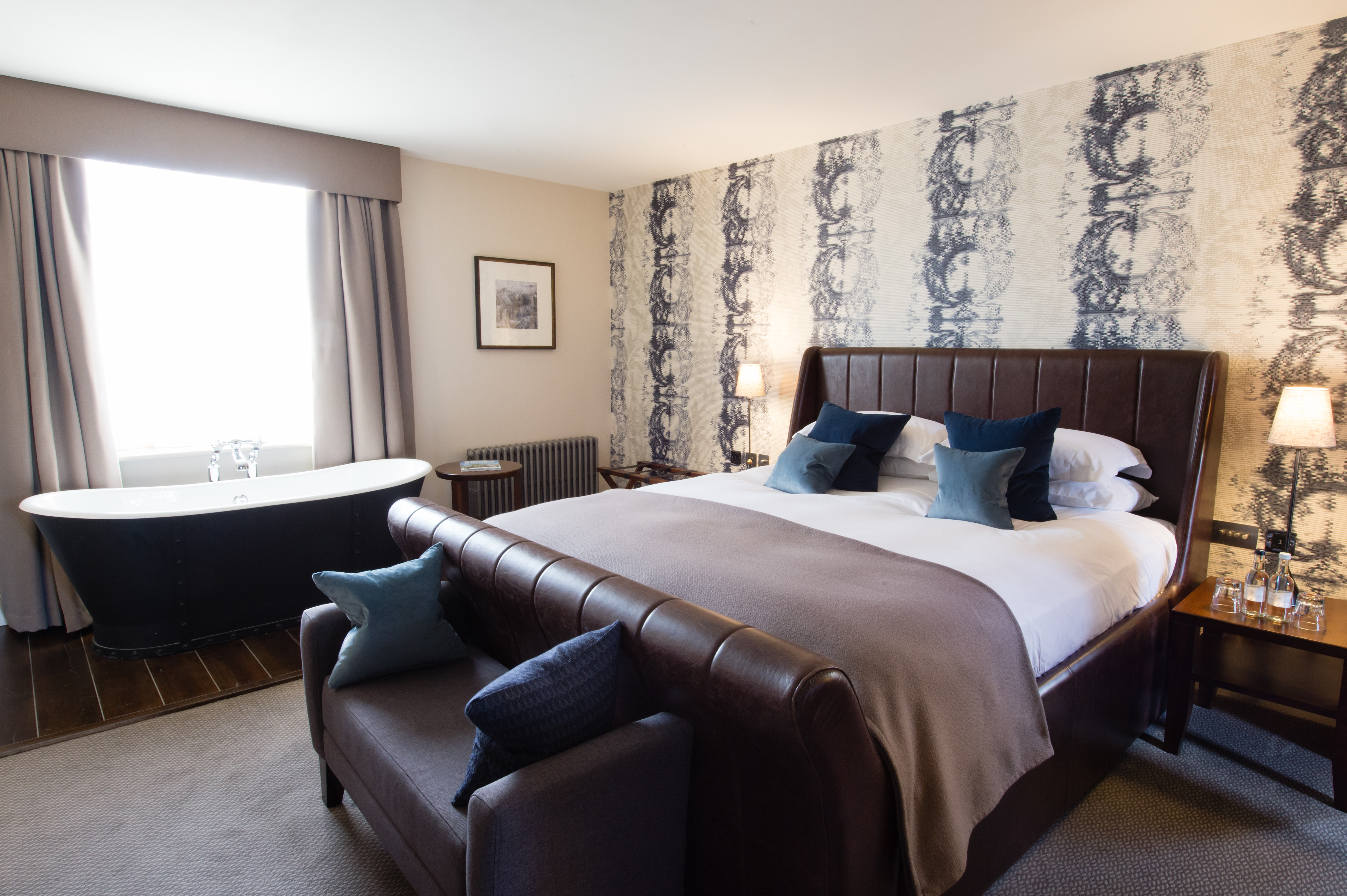 Spacious bedroom featuring a king-sized bed and an elegant bathtub.
