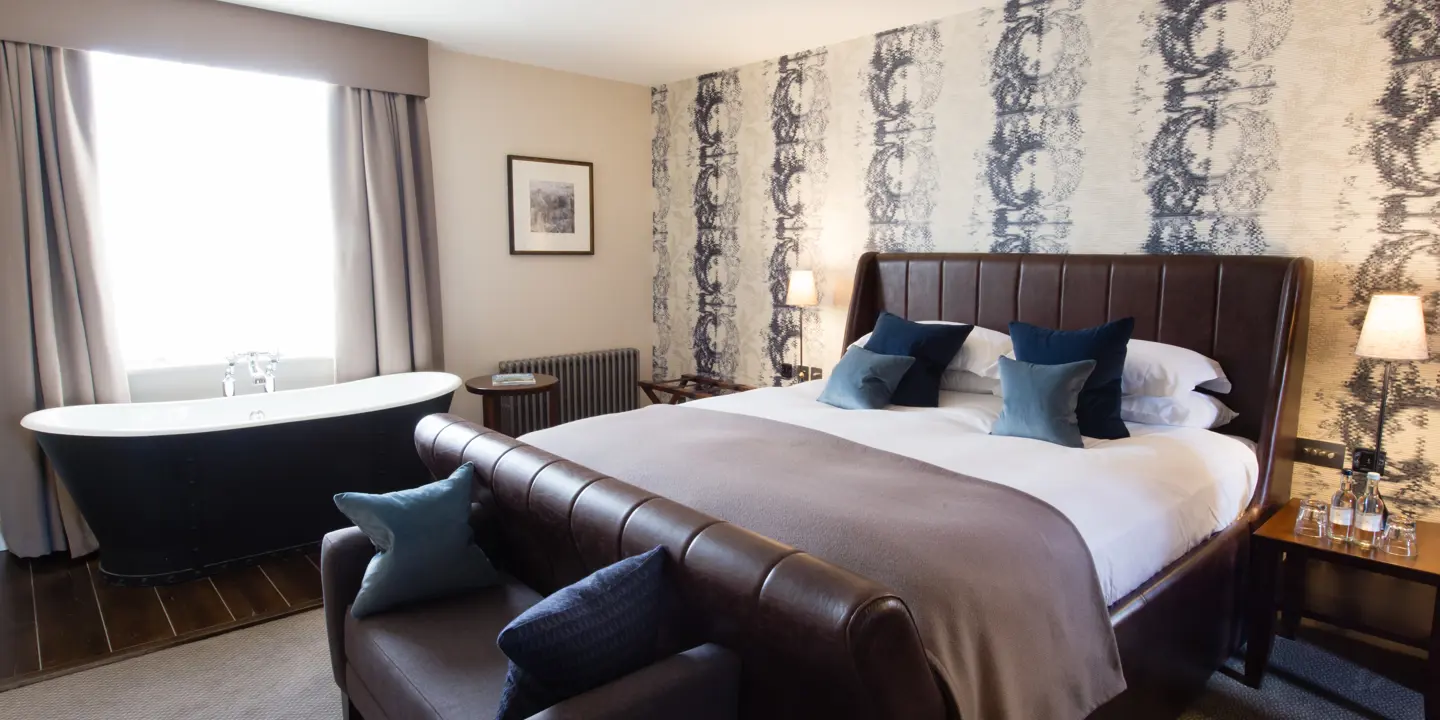 Spacious bedroom featuring a king-sized bed and an elegant bathtub.