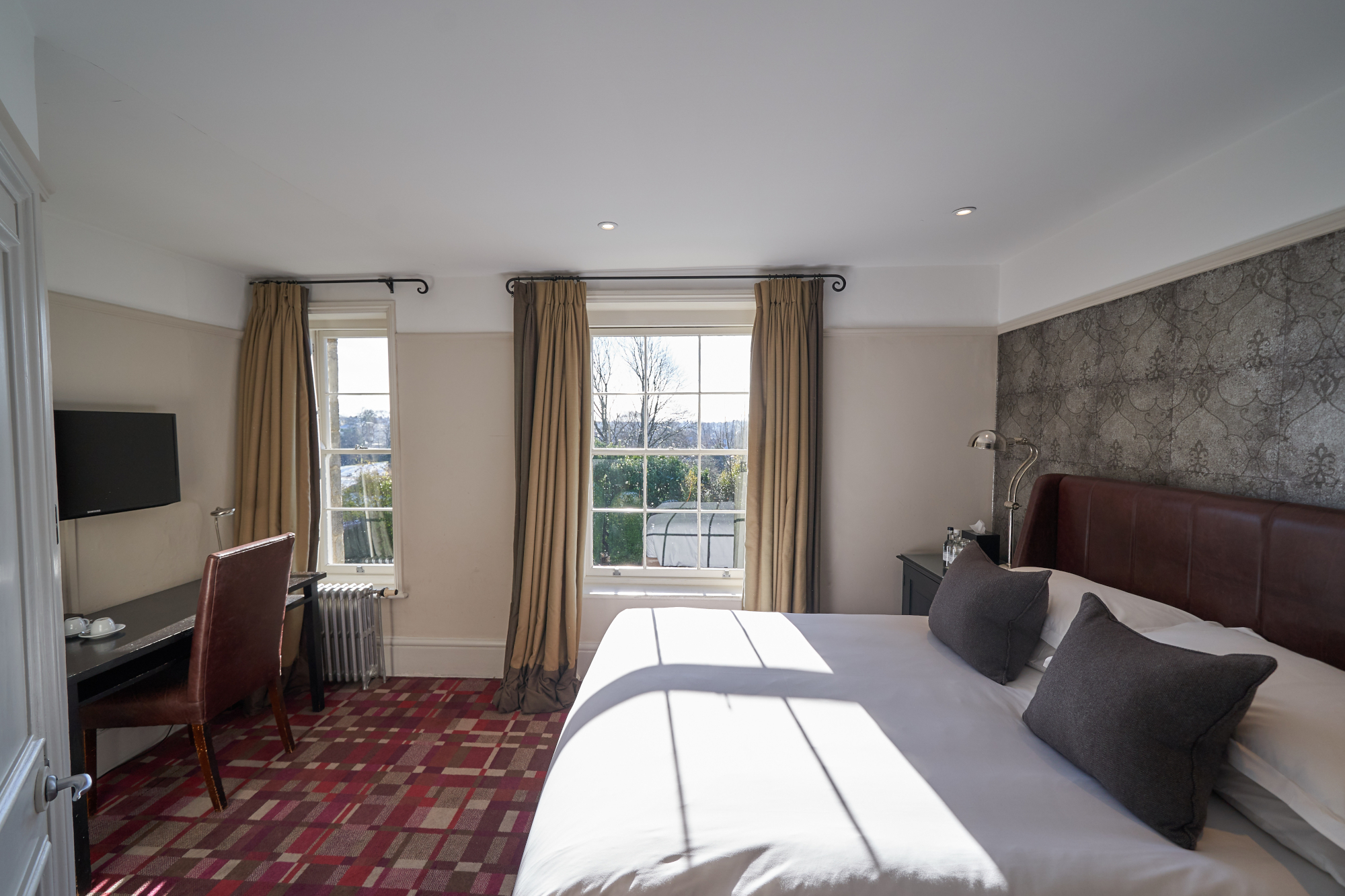 Spacious bedroom featuring a king-sized bed and a functional desk.