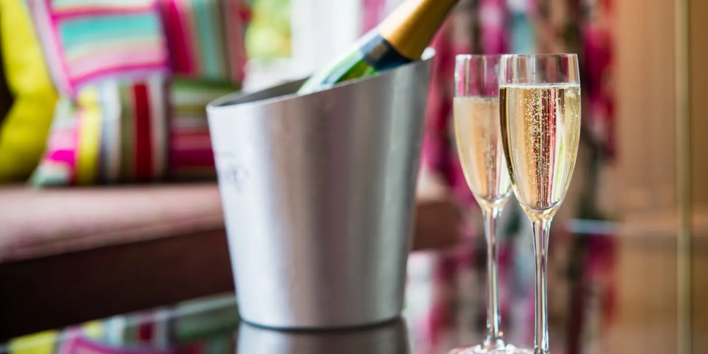 A bottle of champagne and two wine glasses placed on a table.