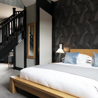 Generously spaced bed with a set of stairs with a dark stained banister