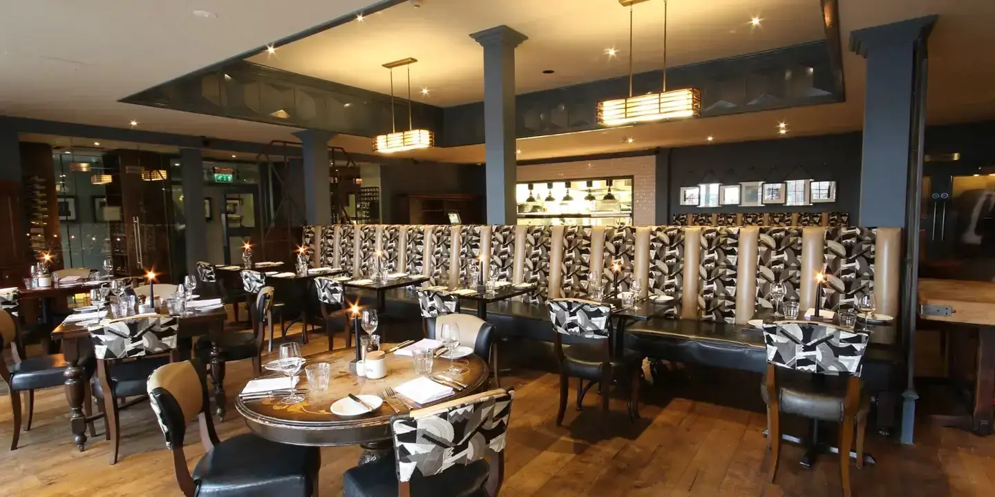 A dining room featuring tables, chairs, and a bar.