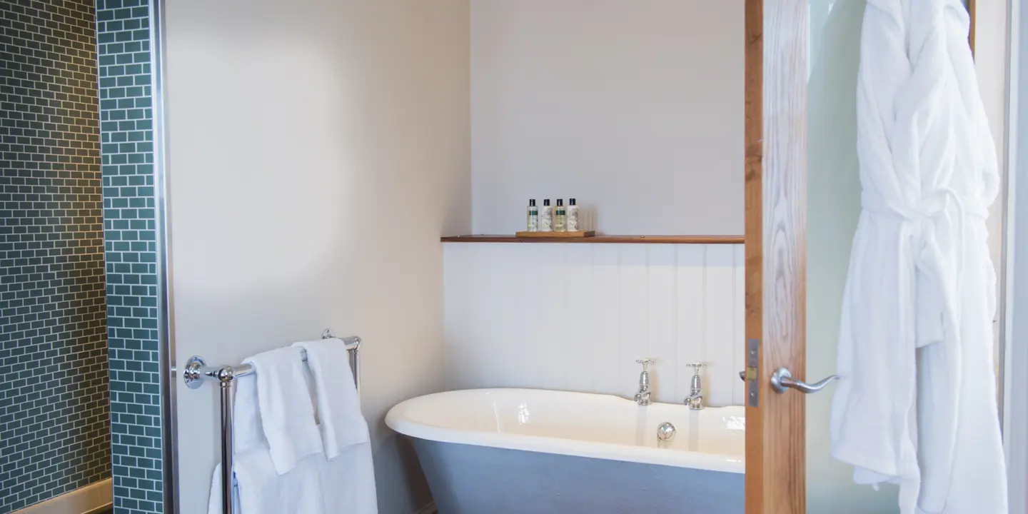 Bathroom featuring a bathtub and sink with dressing gowns hanging on door.