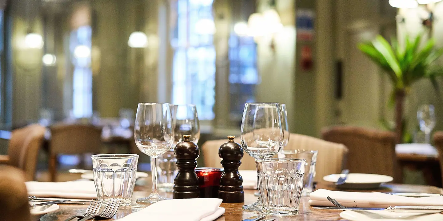 A table adorned with wine glasses, plates, and utensils.