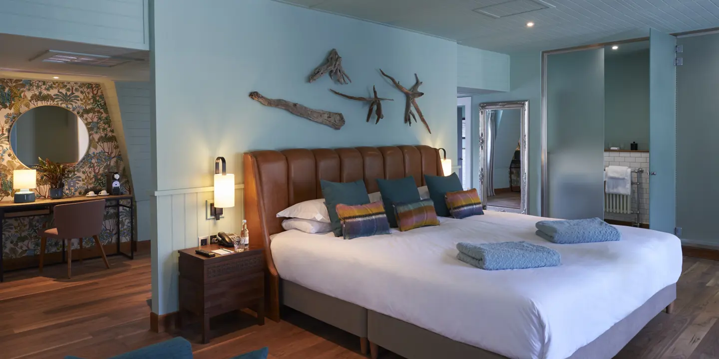 Spacious bedroom featuring a king-sized bed and an elegant chair.