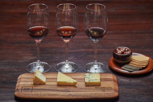 Three glasses of wine behind three pieces of cheese