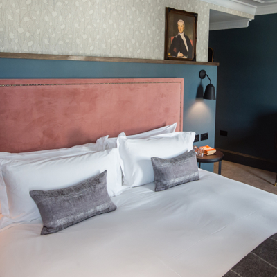 A bed featuring a pink headboard and matching pillows.