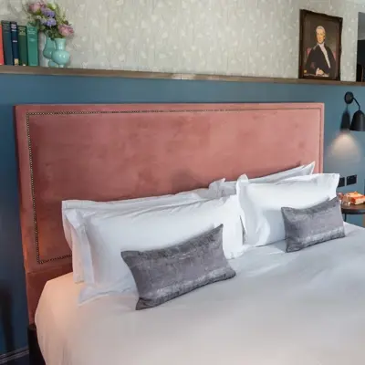 A bed featuring a pink headboard and matching pillows.