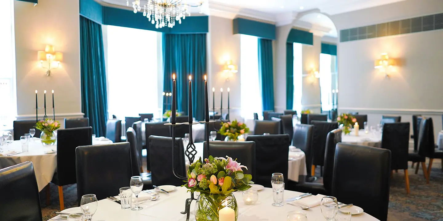 A dining room featuring tables, chairs, and an elegant chandelier.