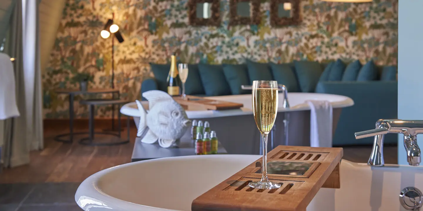 A glass of wine placed on a tray inside a bathtub.