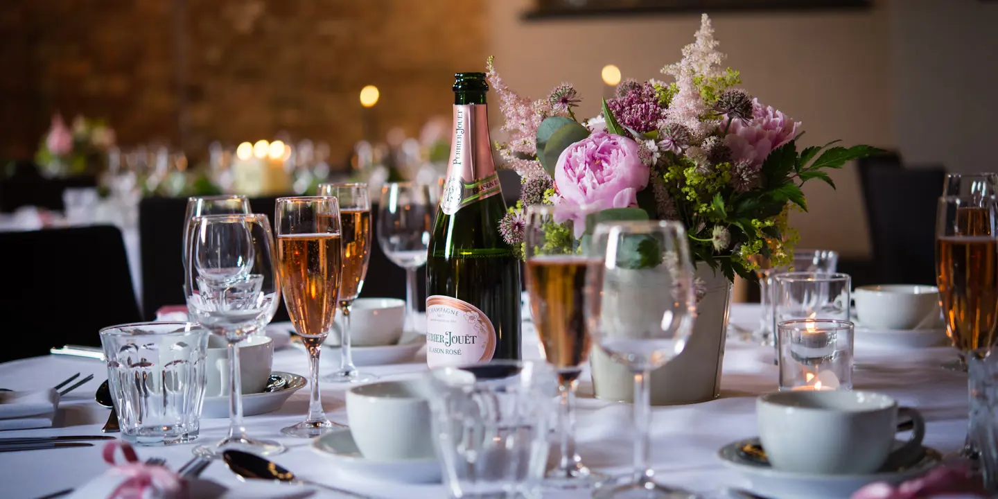 A beautifully arranged table with candles, filled champagne glasses and flowers.