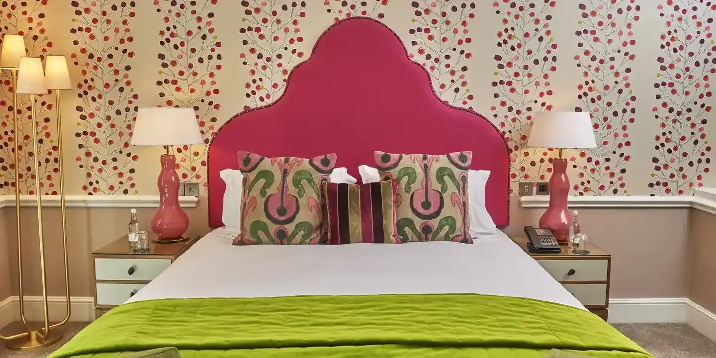 Bed with a pink headboard and vibrant pillows.