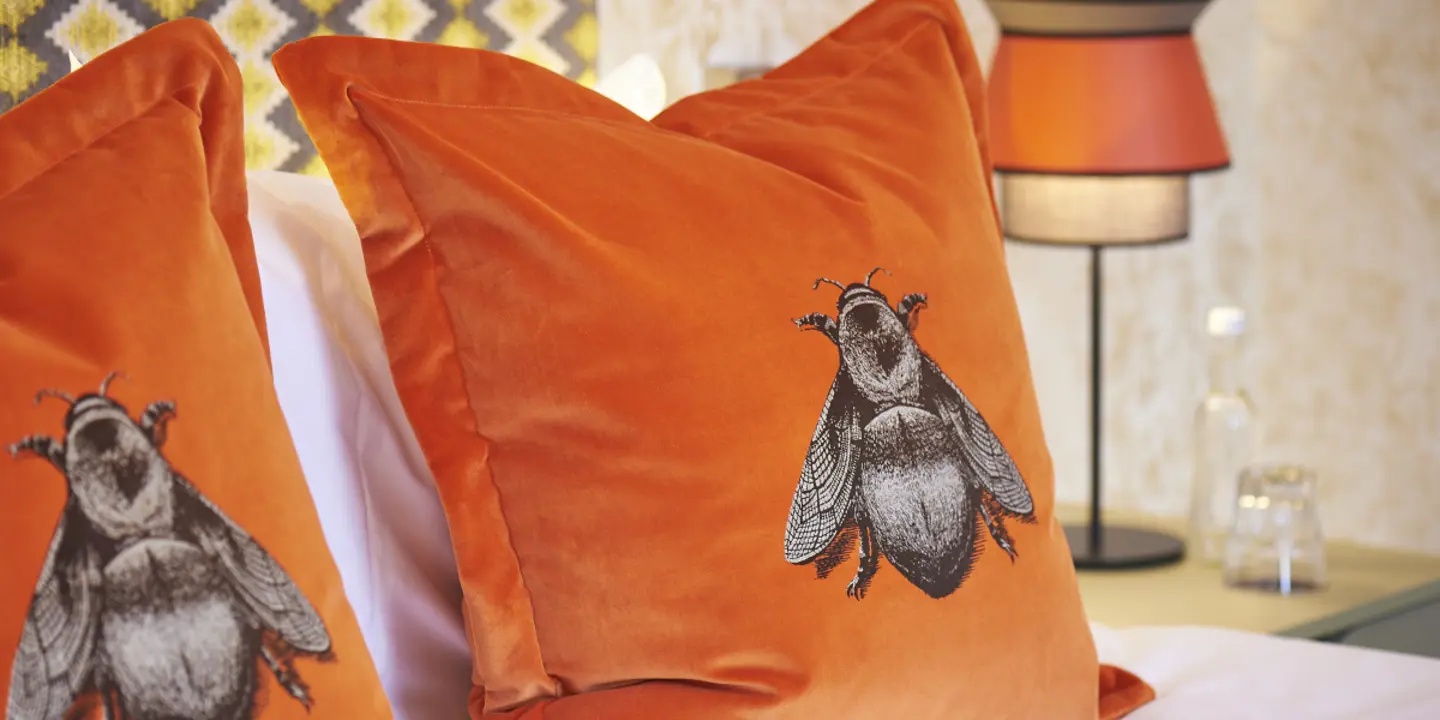 Two bee print pillows placed neatly on a bed.
