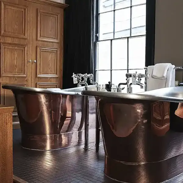 Two large copper bathtubs in a bathroom.
