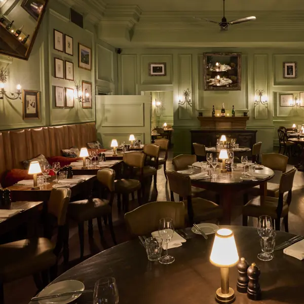 A prepared lowly lit dining hall with wooden tables and chairs