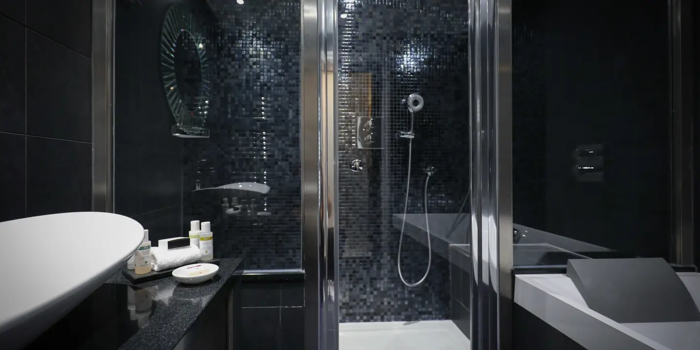 Darkly decorated bathroom featuring a sink, shower, and bathtub.