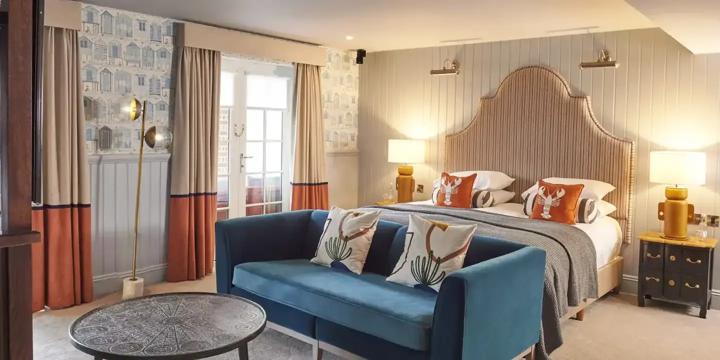 HDV Poole Signature Suite Thierry Lombard with blue sofa and orange bed cushions (1)