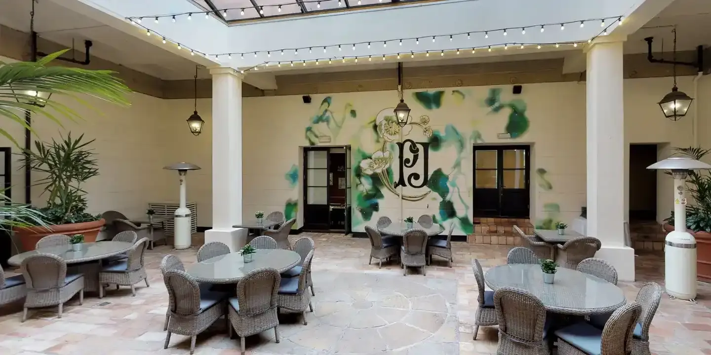 A spacious sky lit dining hall with neutral colours with a section that has a green painted design on the wall