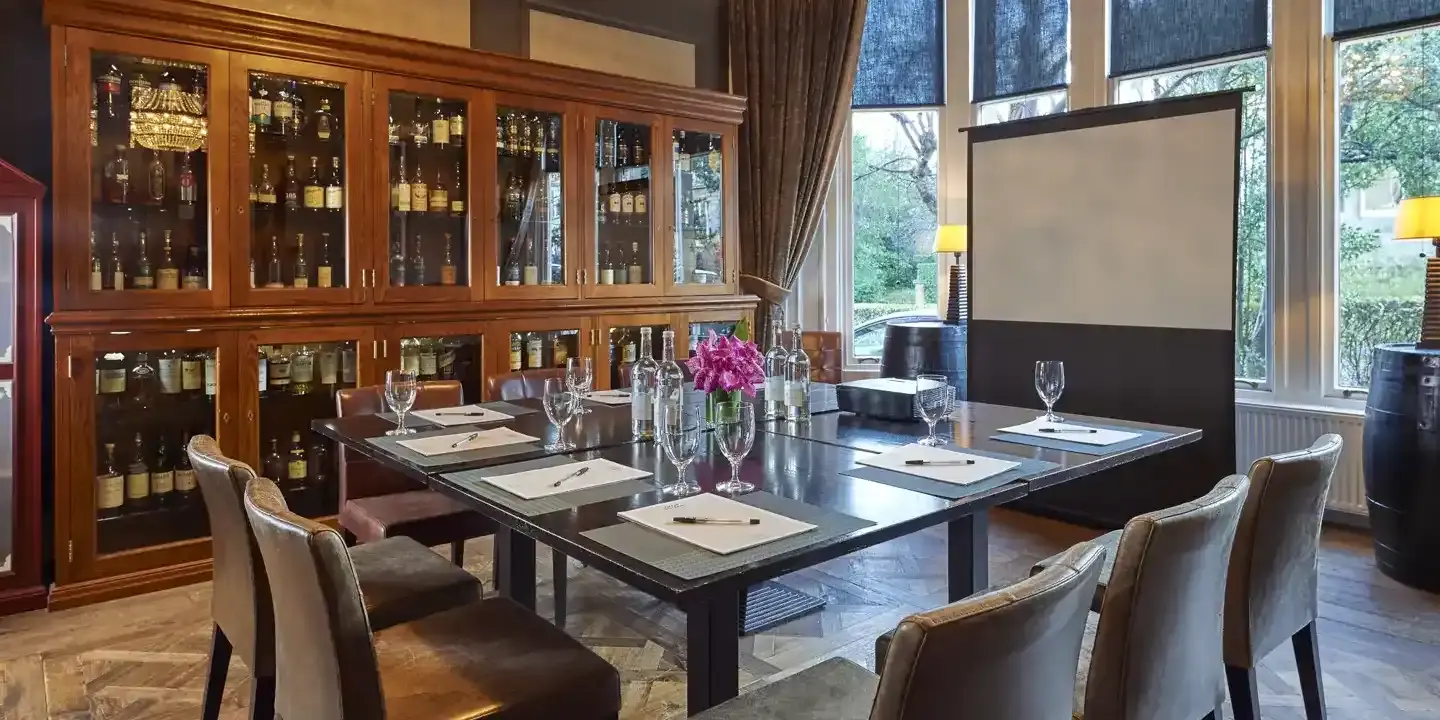 A room adorned with various types of whisky, a small and well furnished table with a projector