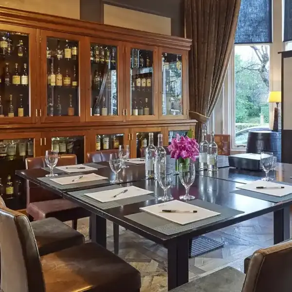 A room adorned with various types of whisky, a small and well furnished table with a projector