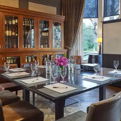 A room adorned with various types of whisky, a small and well furnished table with a projector