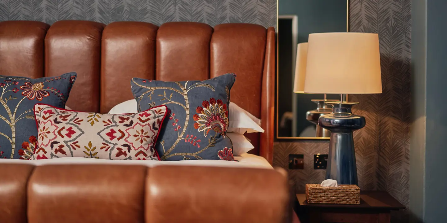 A bed featuring a brown leather headboard and matching pillows.