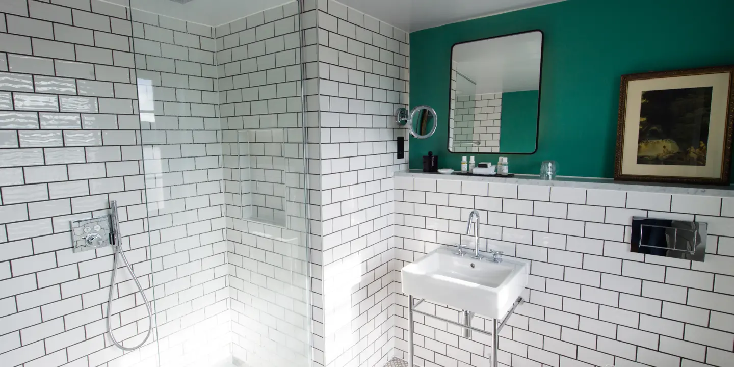 A bathroom with white tiles and a green accent.