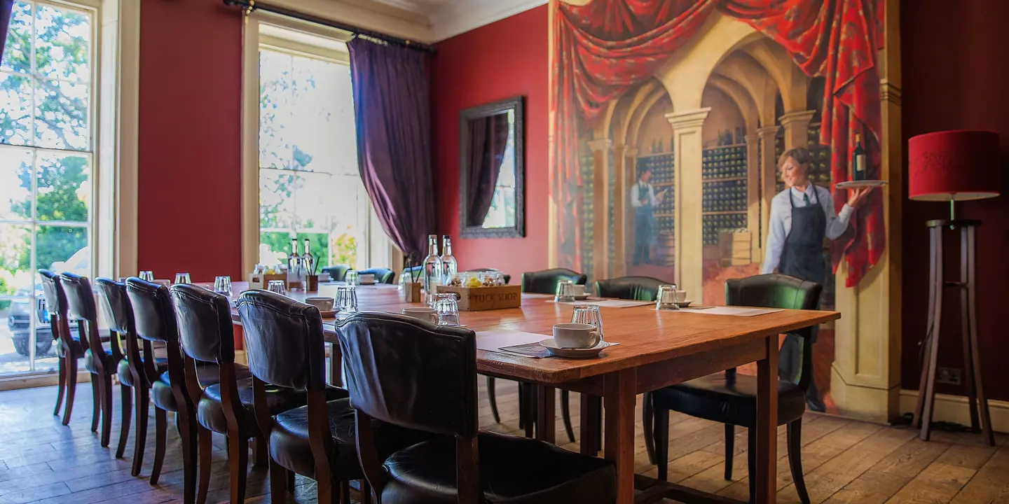 Dining room featuring a prominent wall painting and long wooden table adorned with leather chairs.