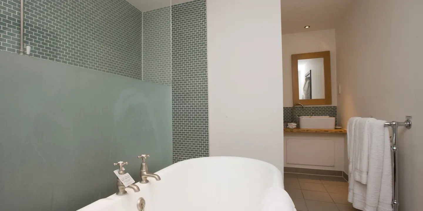 White bathtub positioned in a bathroom alongside a mirror.