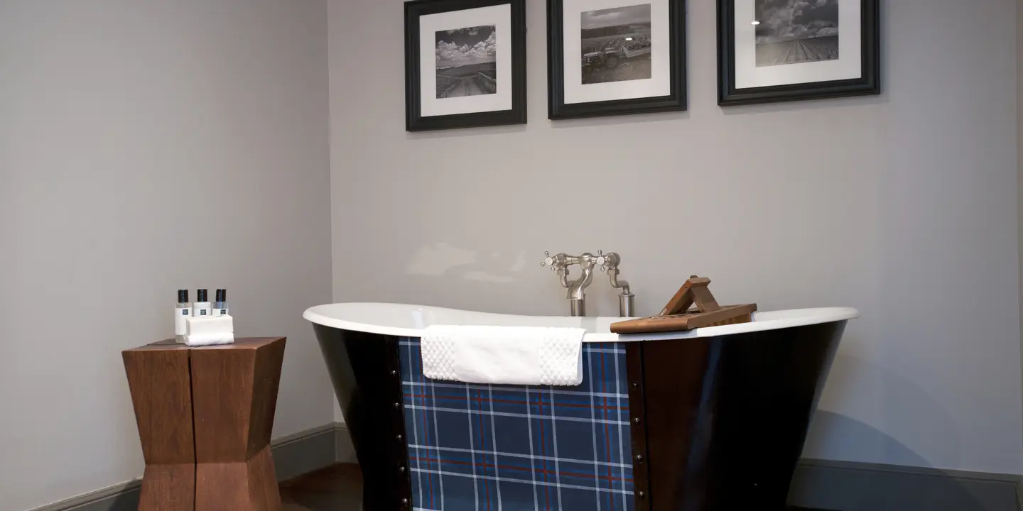 Bath tub placed alongside a wooden stool