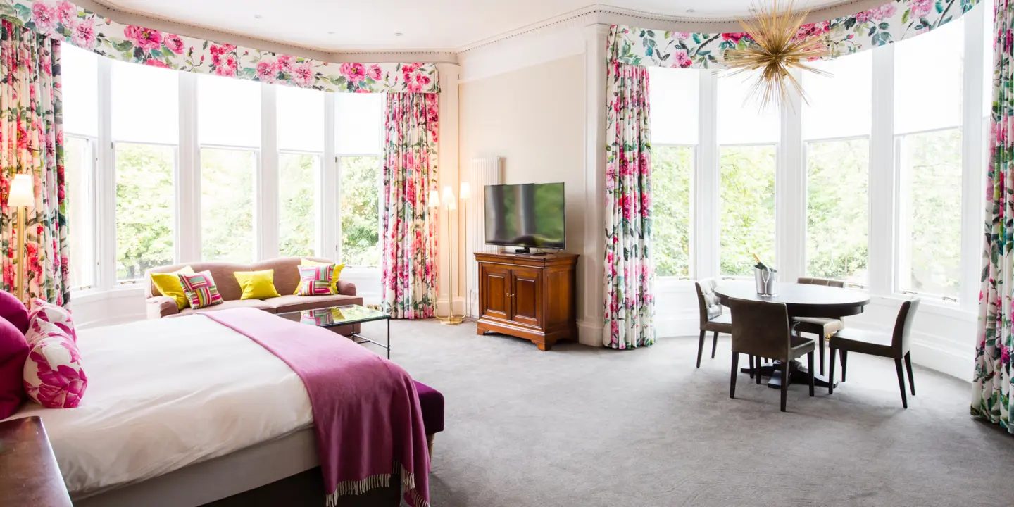 An elegantly furnished bedroom featuring a comfortable bed, stylish chair, sleek table, and modern television.