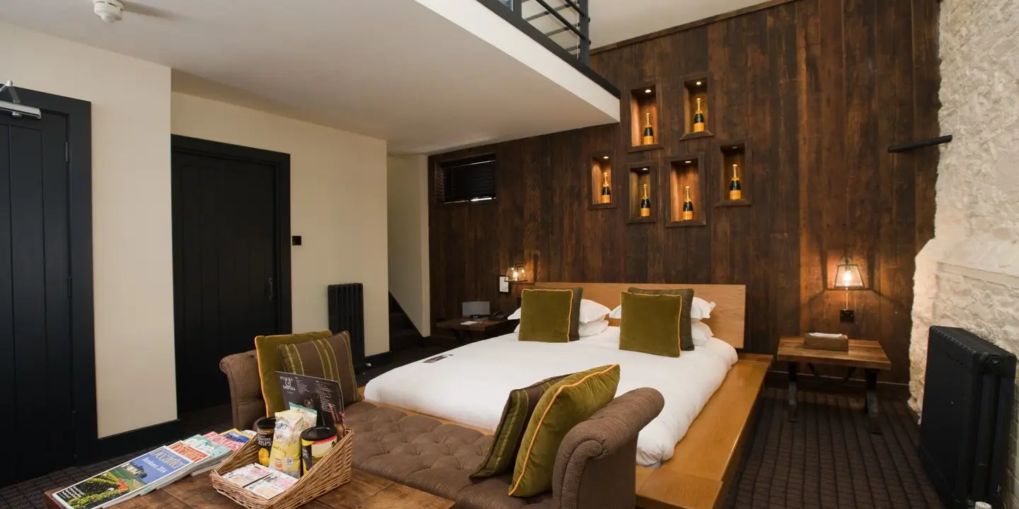 An elegantly furnished hotel room featuring a comfortable bed and a cozy fireplace.