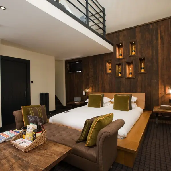 An elegantly furnished hotel room featuring a comfortable bed and a cozy fireplace.