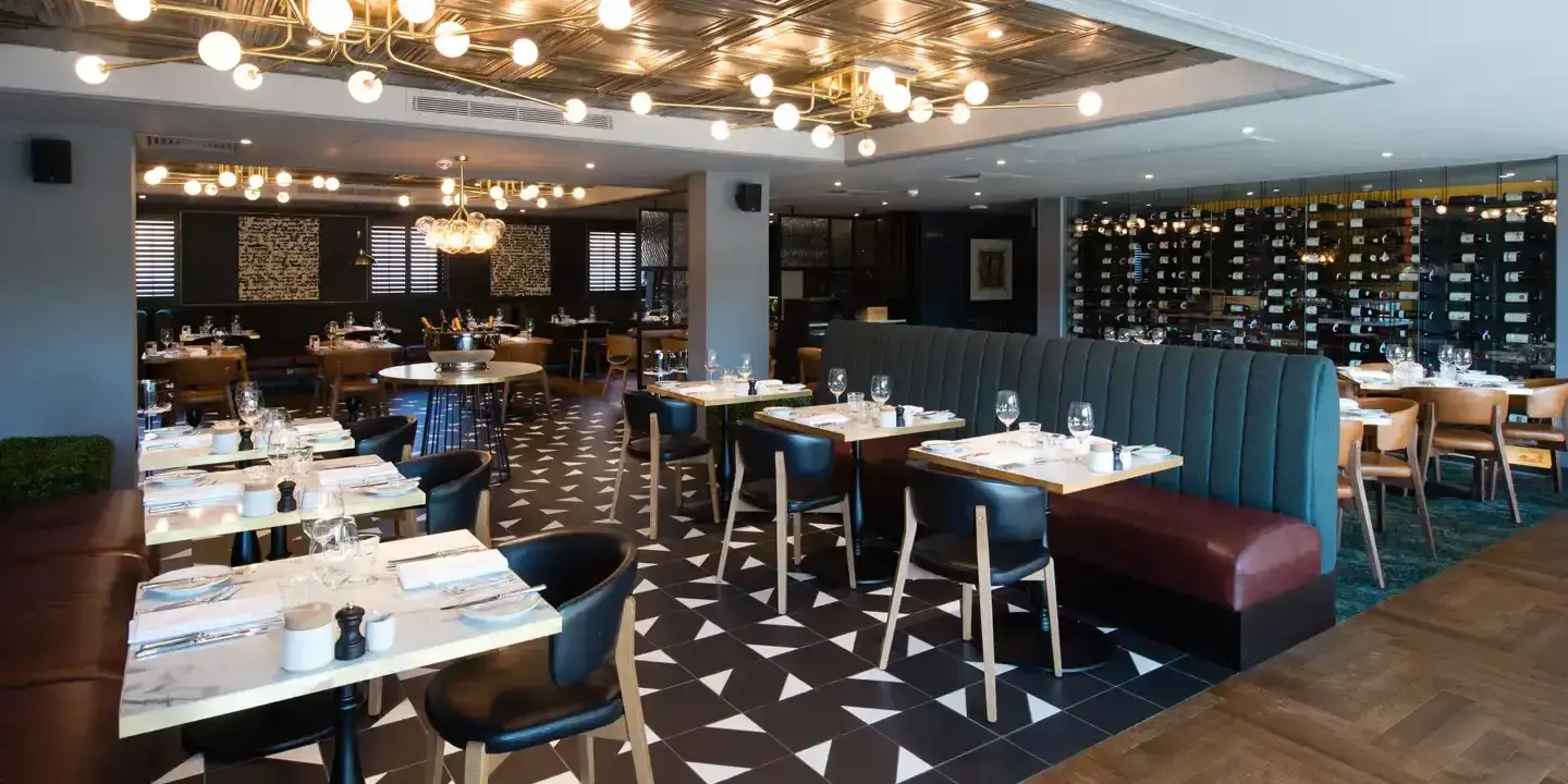 A restaurant featuring tables, chairs, and a large floor to ceiling wine rack.