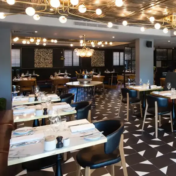A restaurant featuring tables, chairs, and a large floor to ceiling wine rack.