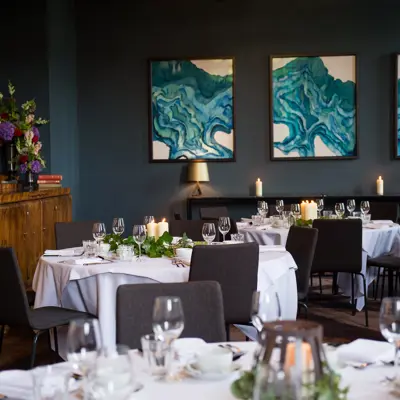 A dining room featuring tables, chairs, and wall paintings.