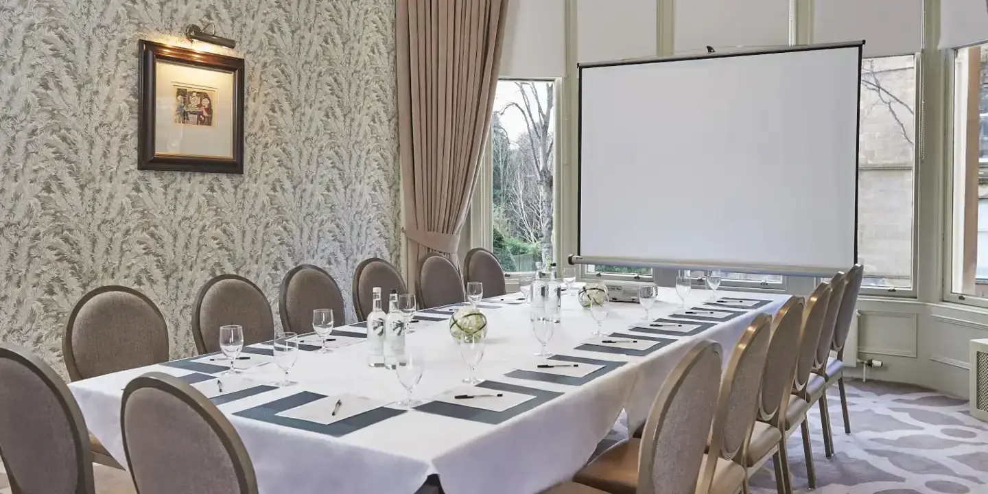 Ardberg room with a long and furnished table and a projector screen