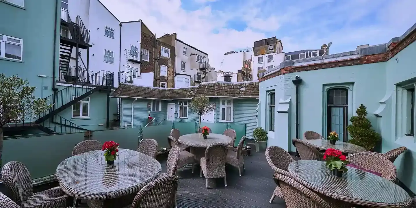 A patio featuring wicker chairs and glass topped wicker tables.